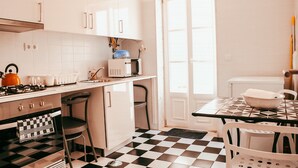 Una cocina con gabinetes blancos, piso a cuadros, estufa, microondas y pileta.