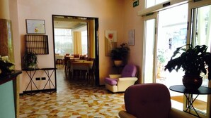 A hotel lobby with a check-in counter, seating area, and a view of the outside. - Hotel Lazzarini (Bellaria-Igea Marina)