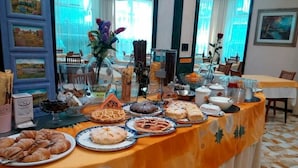 A buffet table with various food items and a decorative centerpiece. - Hotel Lazzarini (Bellaria-Igea Marina)