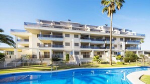 Un hôtel à plusieurs étages doté de balcons, d’une piscine et de palmiers.