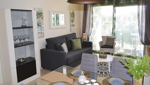 Un salon moderne comprenant un canapé, des fauteuils, une table basse et un meuble vitré contenant des objets décoratifs.