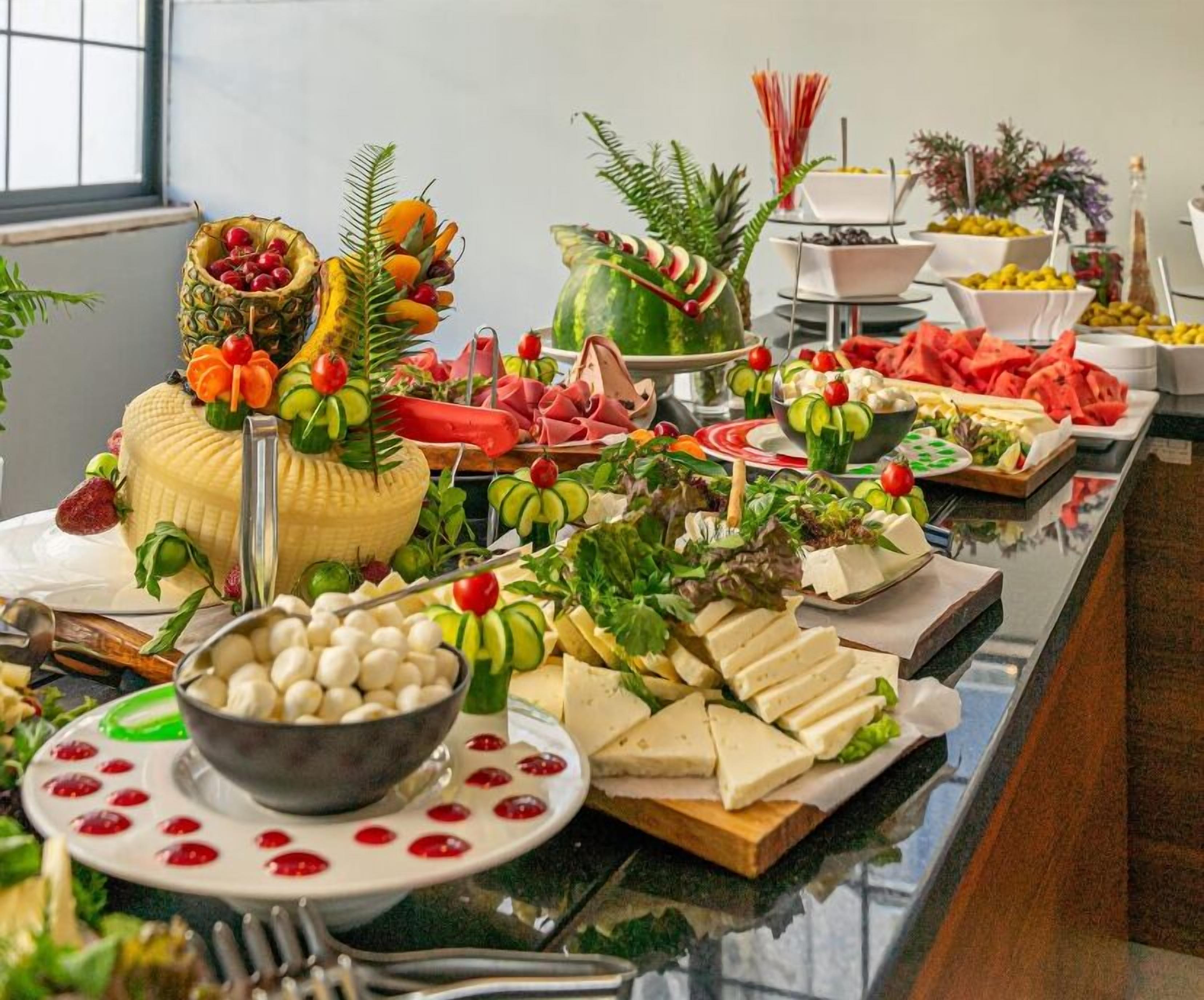 A buffet table with various food items including fruits, cheeses, and salads.