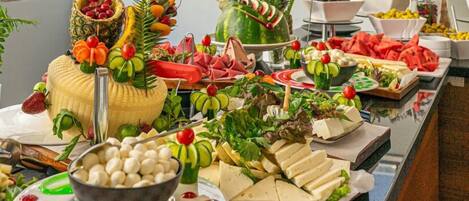A buffet table with various food items including fruits, cheeses, and salads.
