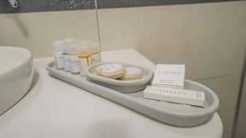 Un baño con una bandeja que contiene artículos de aseo, incluyendo botellas y jabones, y un cartel que dice 'Auzasia Hotel'.