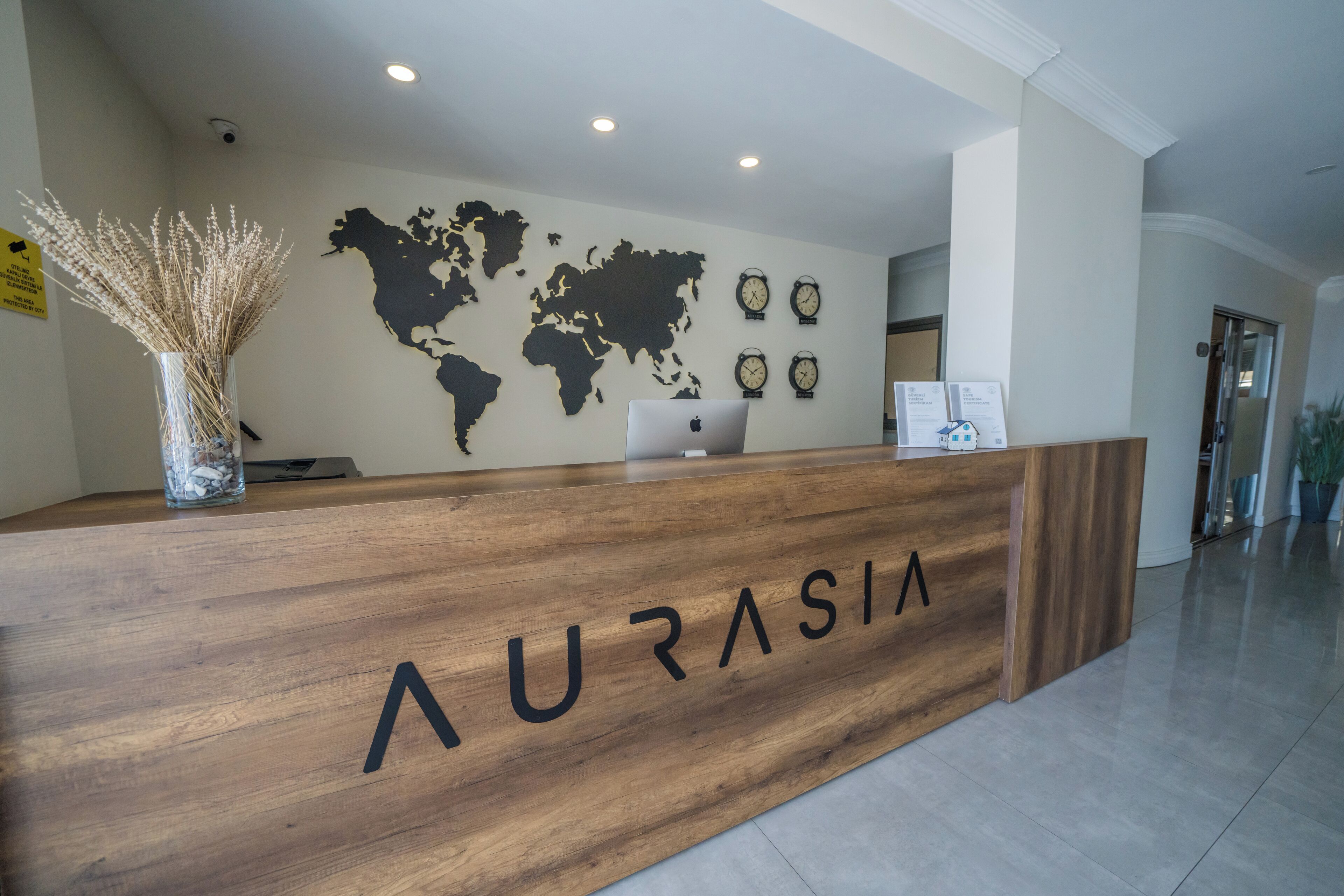 Ein Empfangstresen mit der Aufschrift 'AURASIA', eine Weltkarte an der Wand und Uhren.
