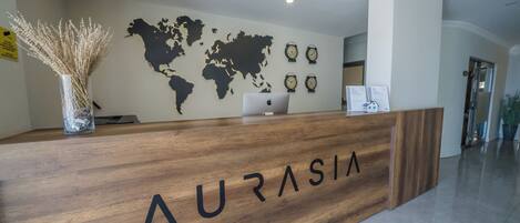 Una recepción con el nombre "AURASIA", un mapa del mundo en la pared y relojes.