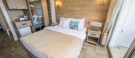 Una habitación de hotel con una cama grande, cabecera de madera, mesitas de noche, un armario y un espejo.