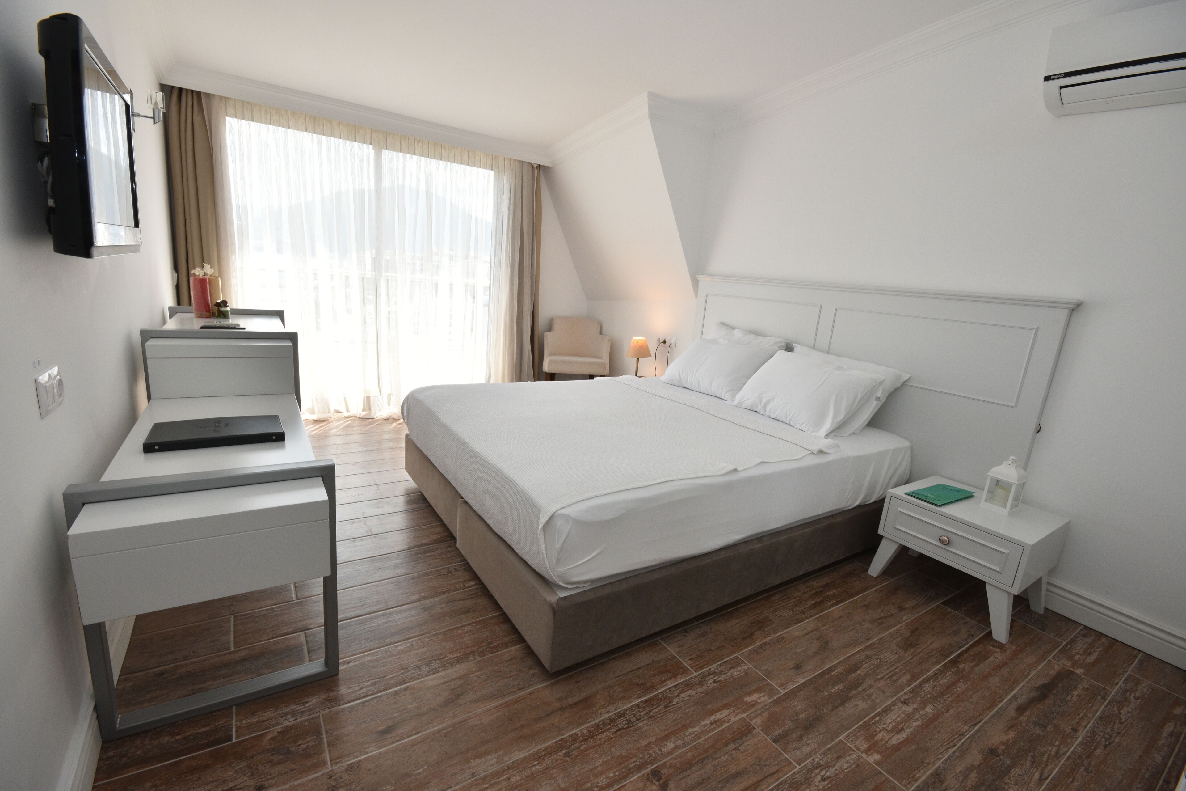 A modern hotel room with a large bed, a desk, and a chair.