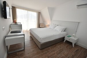 A modern hotel room with a large bed, a desk, and a chair.