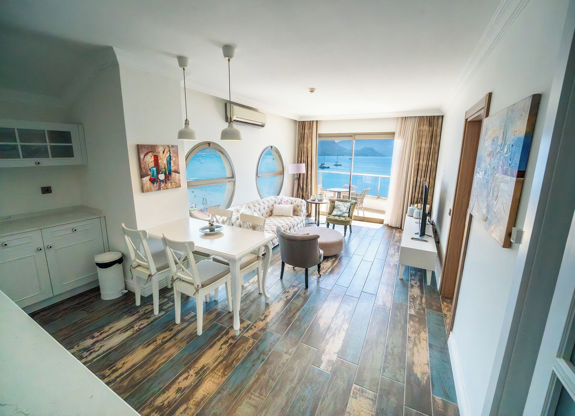 Un interno moderno con zona pranzo, divanetto e ampie finestre vista mare.