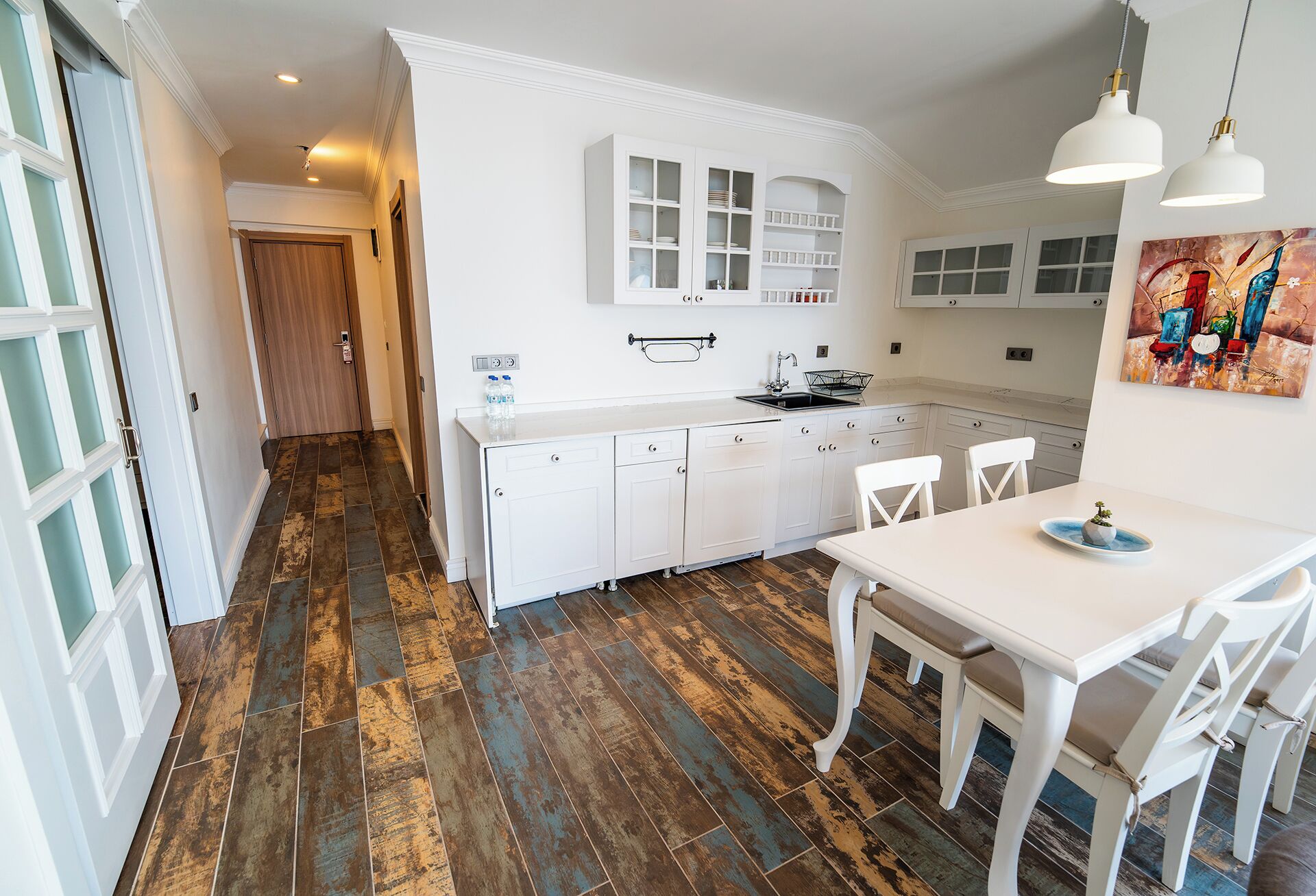A kitchen with white cabinets, a sink, and a dining area with a table and chairs.