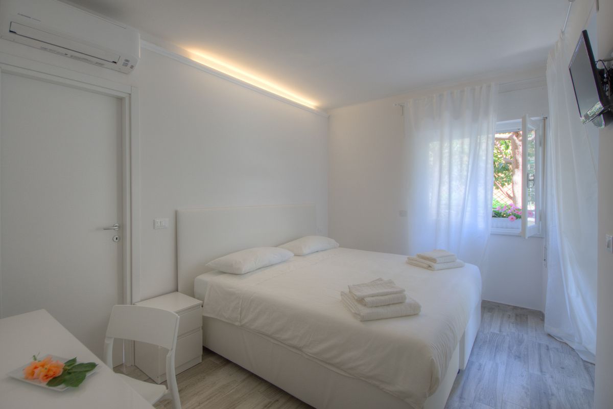A minimalist bedroom with a bed, bedside table, and a window with curtains.