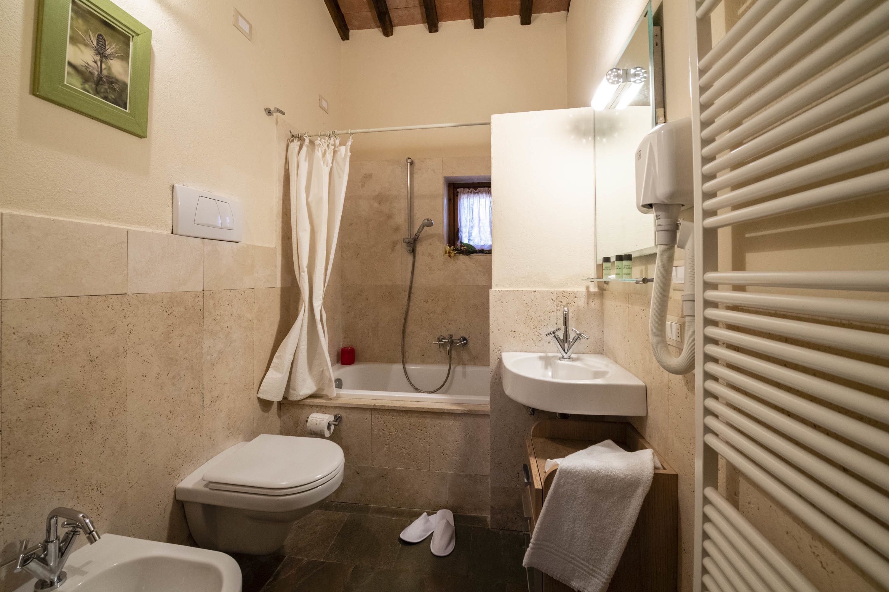 Un bagno con vasca, servizi igienici, lavandino e porta asciugamani.