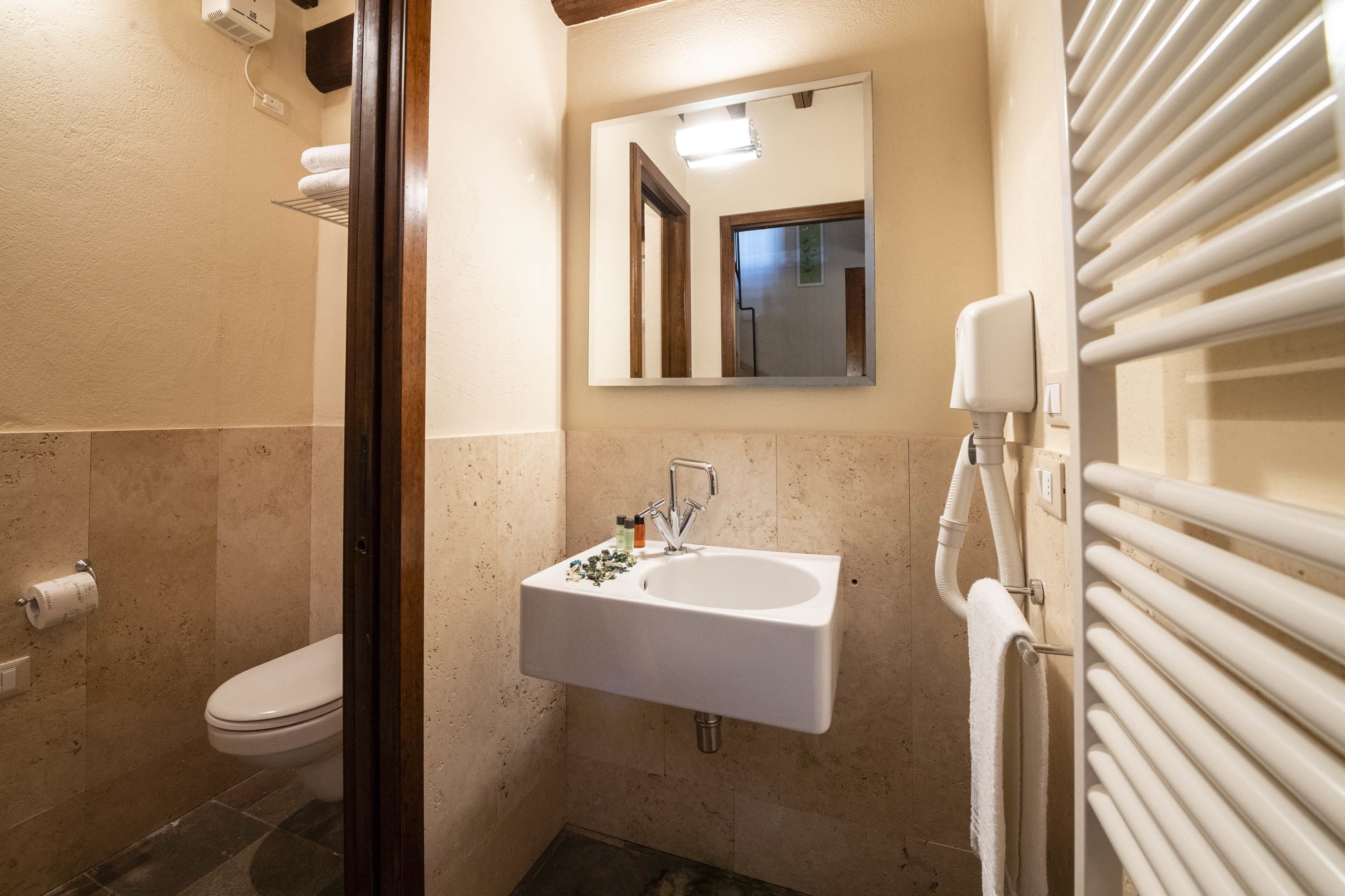 A small bathroom with a toilet, sink, and mirror.