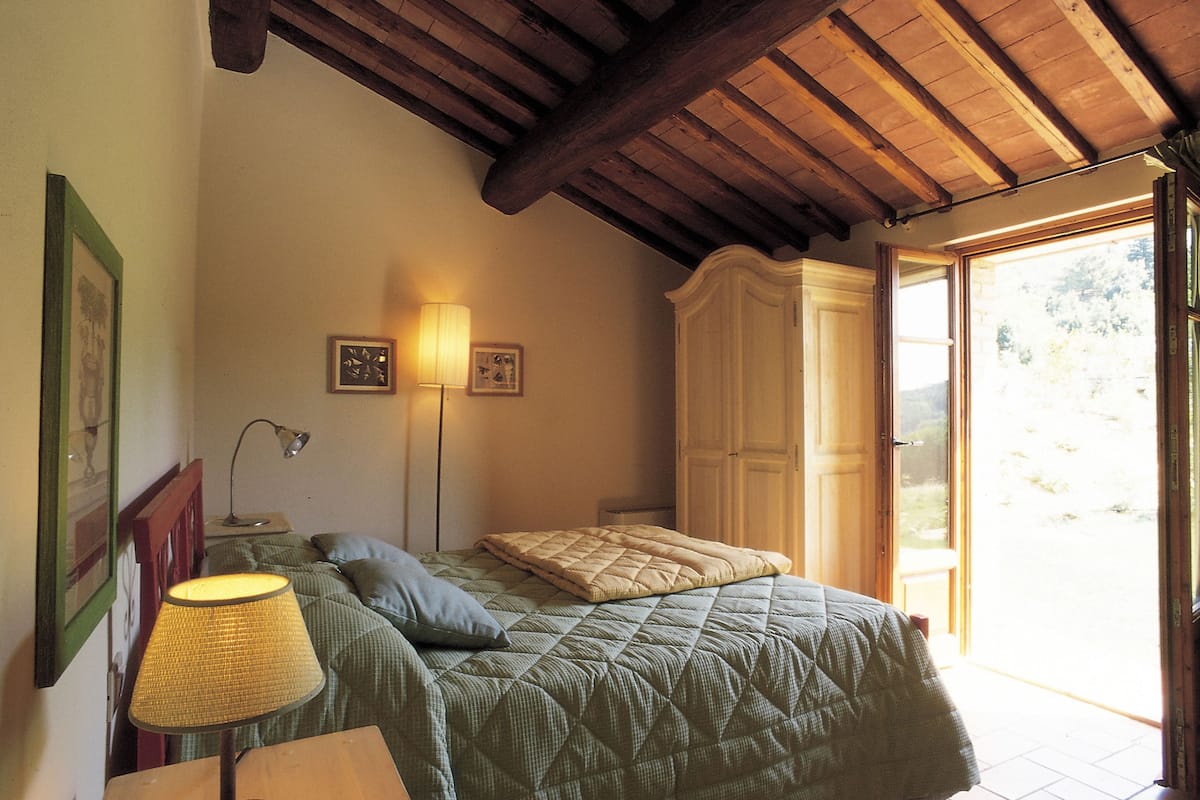 A bedroom with a bed, a nightstand, a lamp, and a wardrobe.