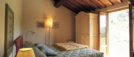A bedroom with a bed, a nightstand, a lamp, and a wardrobe.
