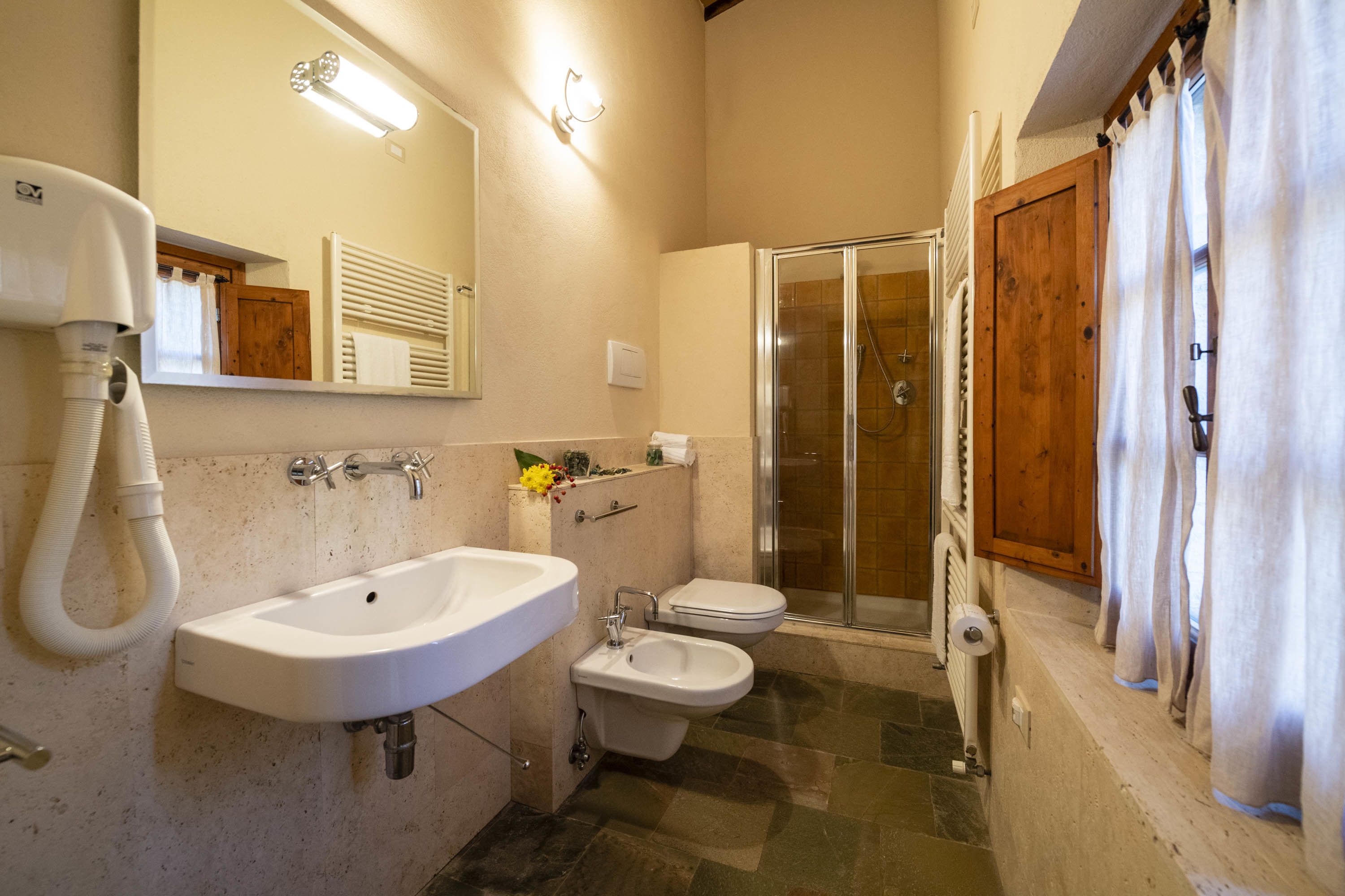 A bathroom with a sink, bidet, toilet, and a glass shower enclosure.