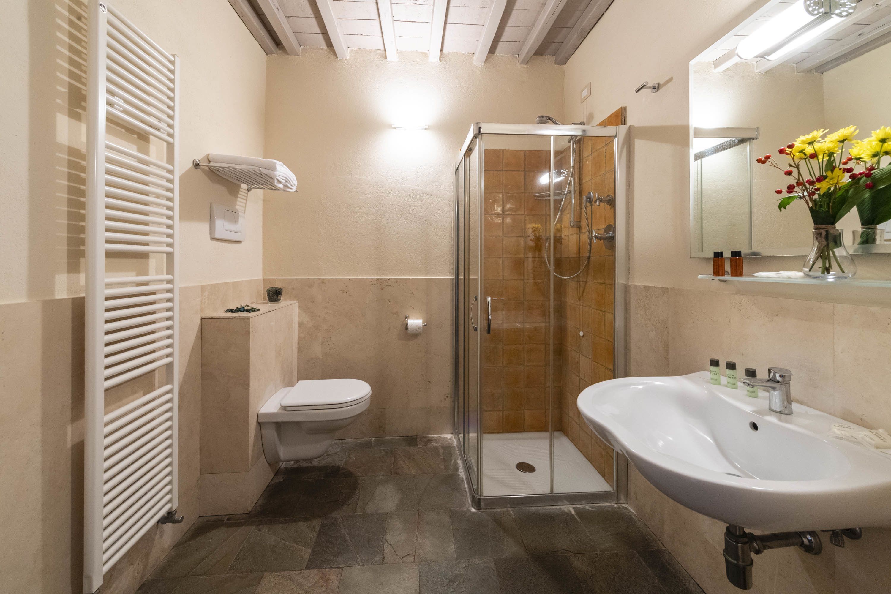 A bathroom with a glass-enclosed shower, a white sink, and a toilet.
