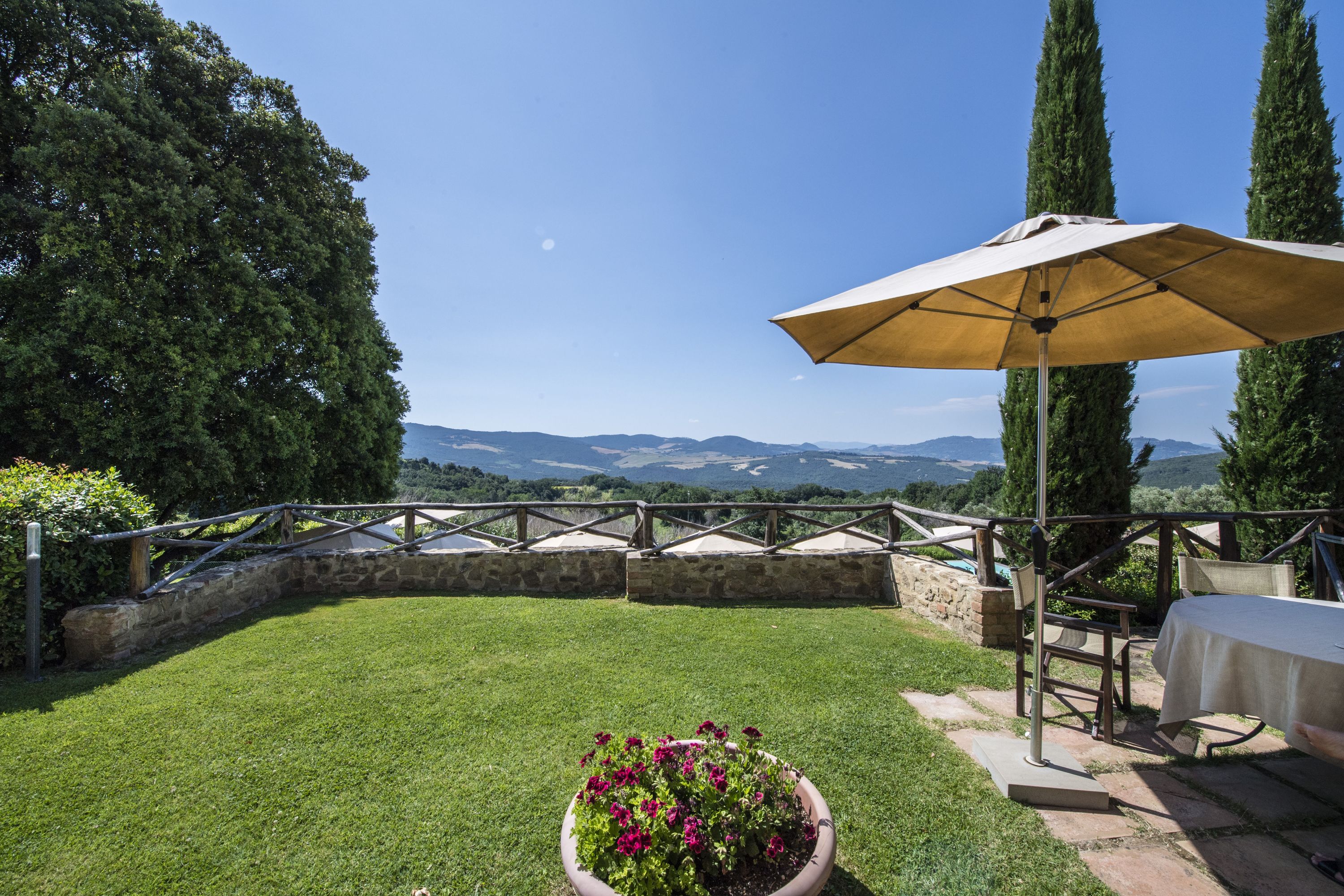 Un patio con una mesa, sillas, una planta en maceta y vistas al campo.