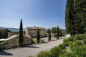 A stone building with a tiled roof, surrounded by greenery and a gravel path. - Il Defizio (Gambassi Terme)