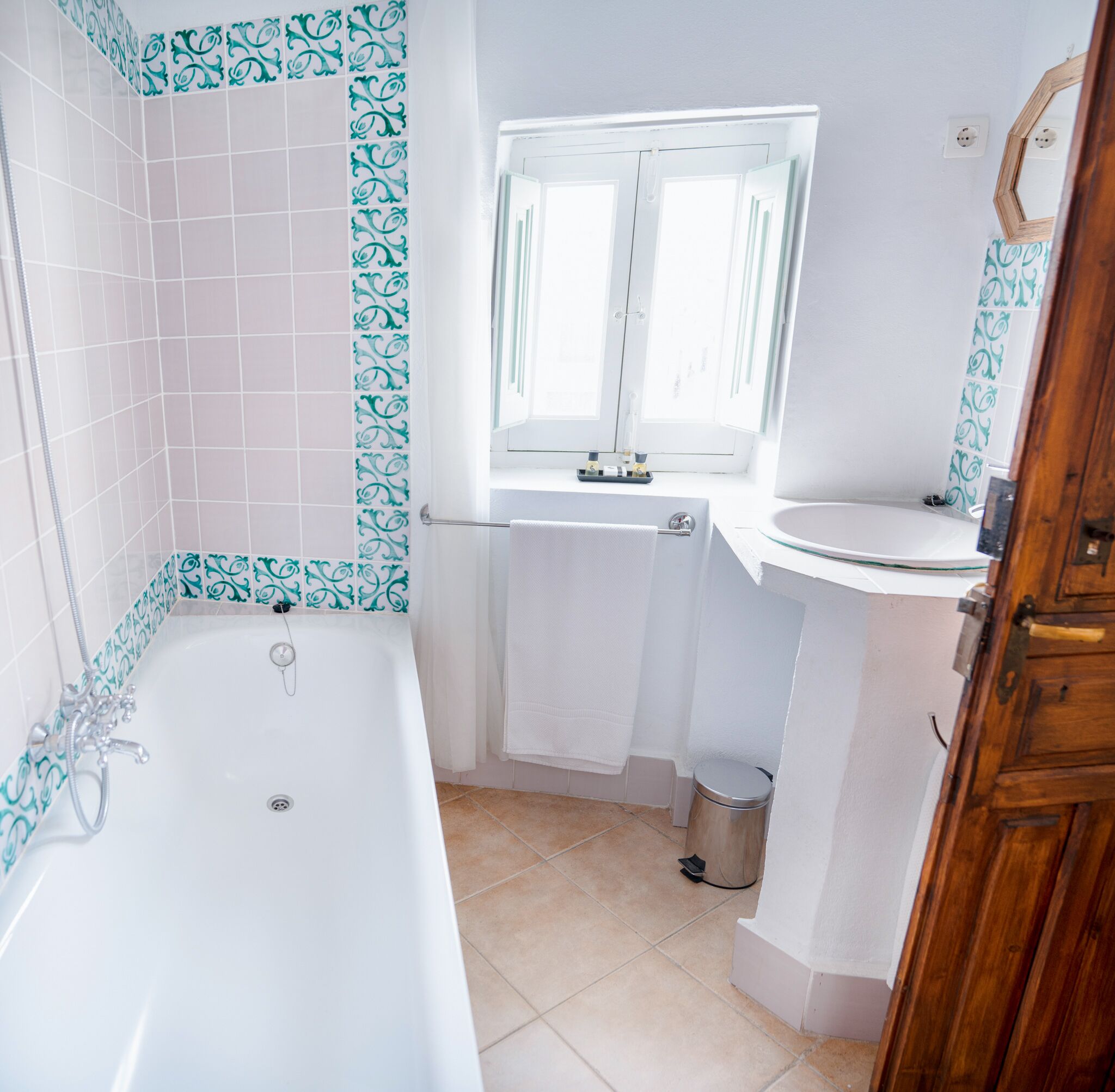A bathroom with a bathtub, a window, a sink, and a mirror.