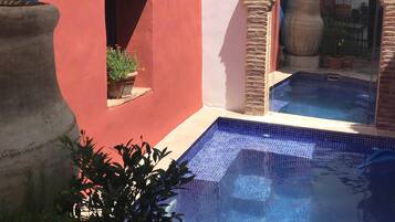 A pool area with a tiled floor, a potted plant, and a stone archway.