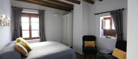 A bedroom with a bed, a chair, a small table, and a wardrobe.