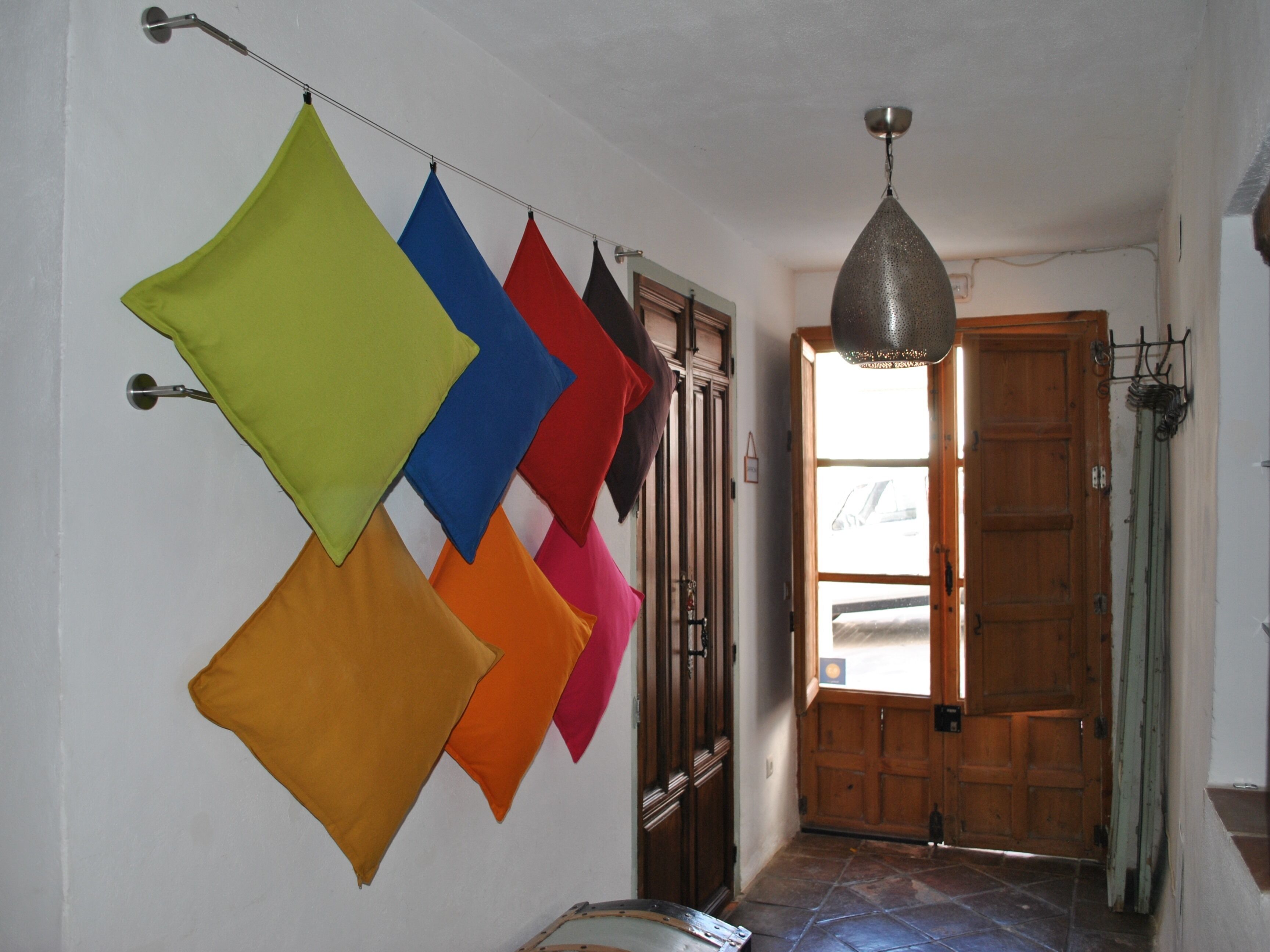 A hallway with a wooden door, a hanging light fixture, and a wall with colorful geometric shapes.