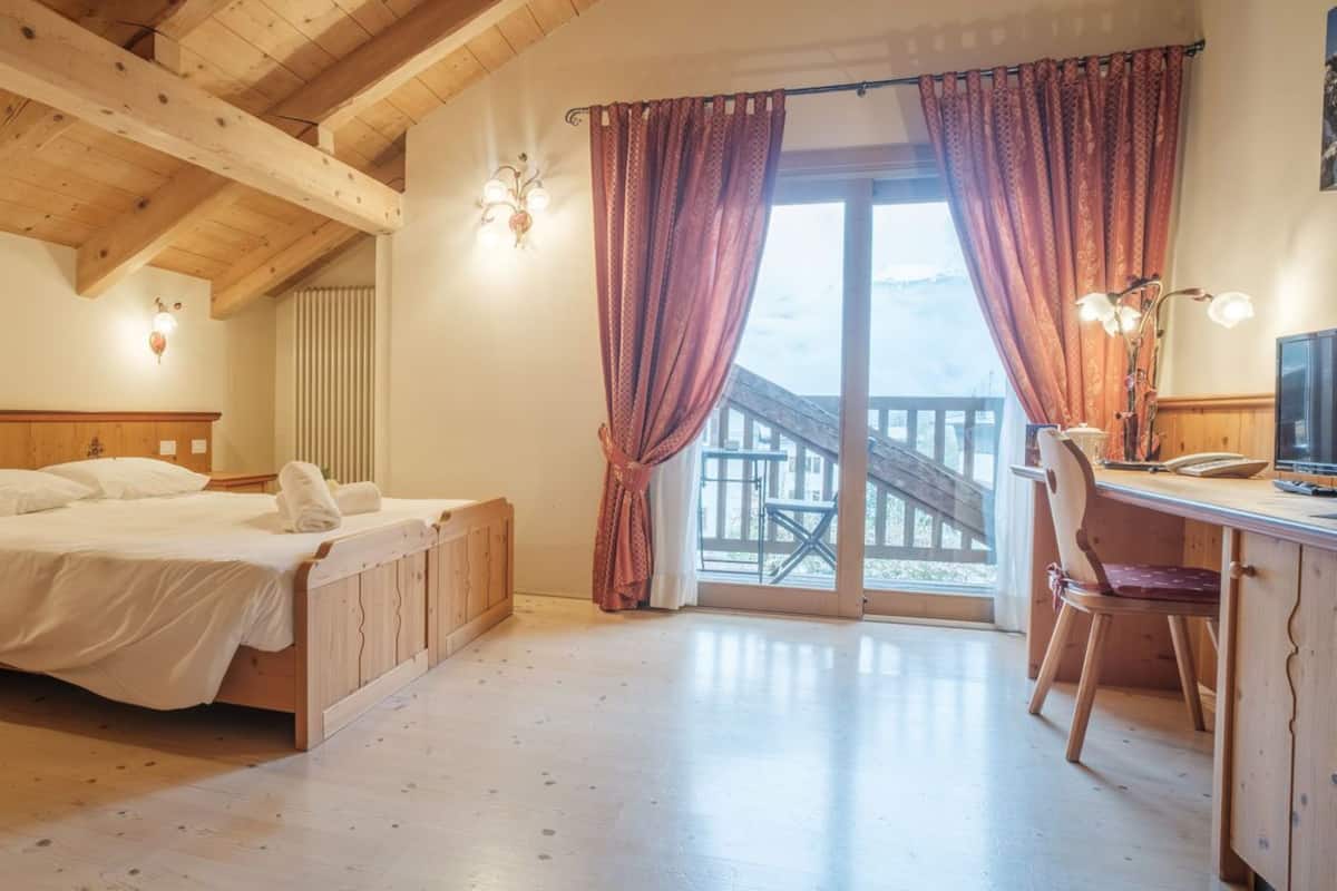 Un dormitorio con cama de madera, un escritorio y vistas a un balcón.