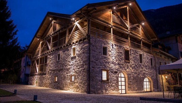 A stone building with wooden beams and multiple windows, likely a hotel or lodge. - Casa Moresc (Spiazzo)