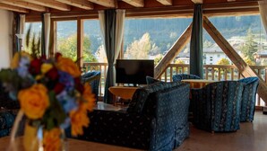 A cozy room with a wooden ceiling, a TV on a stand, and a sofa set. - Casa Moresc (Spiazzo)