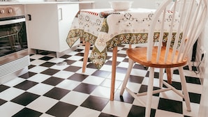 A kitchen with a checkered floor, white cabinets, a microwave, and a table with a floral tablecloth. - Kalathos House 3 By Gt House (Lisboa ciudad)