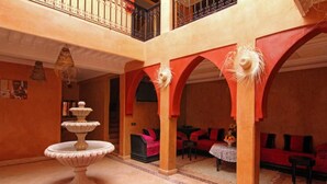 A spacious interior with a fountain, red arches, and a cozy seating area. - Villa Tigmi (Ourika)