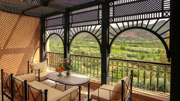 A covered outdoor seating area with a table and chairs, overlooking a lush green landscape. - Villa Tigmi (Ourika)