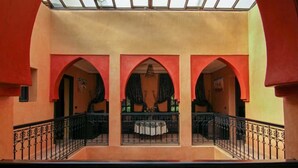 A building with a central courtyard featuring three arches, a balcony with a table, and a view through the arches. - Villa Tigmi (Ourika)