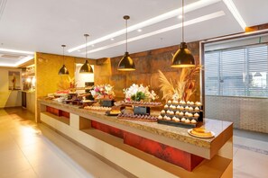 Un área de recepción bien iluminada con un mostrador que exhibe diferentes pasteles y flores.