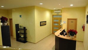 Zona de recepción con mostrador, extintor, puerta privada y señalización de salida.