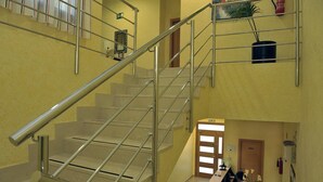 Interior de varios niveles con una escalera de metal, una recepción y una puerta señalizada como 'EXIT'.