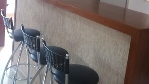 Una zona de cocina con encimera de madera, tres taburetes de metal y un refrigerador blanco.