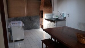 Una cocina con horno de ladrillo, armarios blancos, un fregadero y una mesa con bancos.