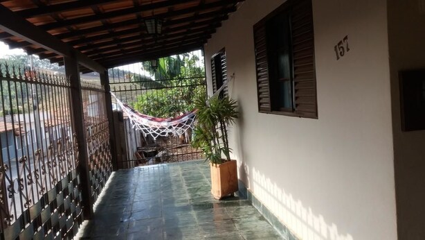 Un balcón techado con una hamaca, una planta en maceta y el número '157' en la pared.