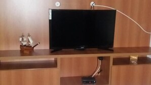 Una sala de estar con un mueble de madera para entretenimiento, un televisor de pantalla plana y un pequeño modelo de barco.