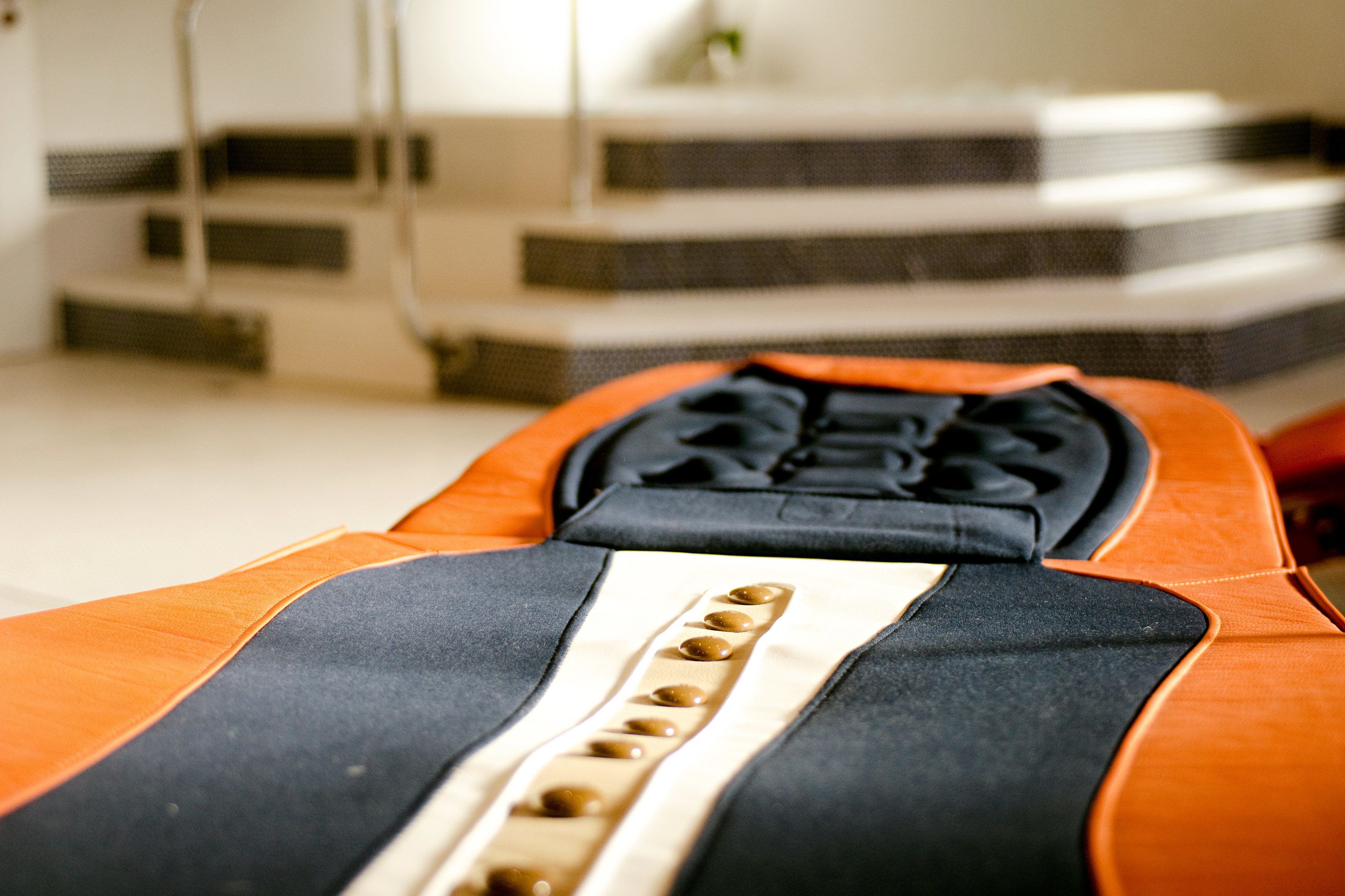 A close-up of a bed with an orange and black cover, featuring a headboard with a unique design and a series of buttons.