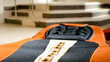 A close-up of a bed with an orange and black cover, featuring a headboard with a unique design and a series of buttons.
