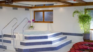 A hot tub with steps, a window, and a potted plant. - Hotel Mutzel (Schluchsee)