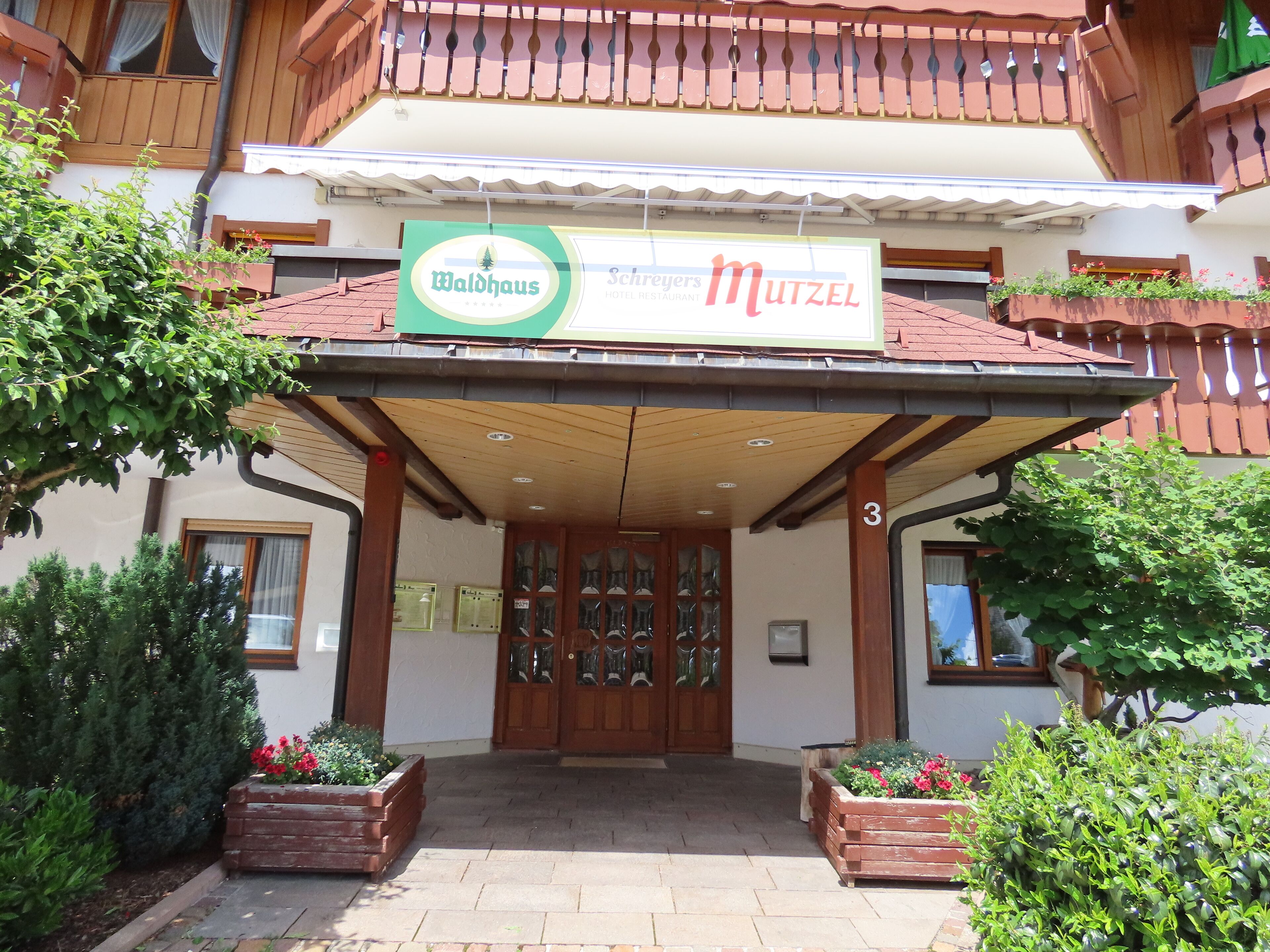 Entrada de un hotel con un letrero que dice 'Waldhaus' y 'Schreijers Mutzel'.