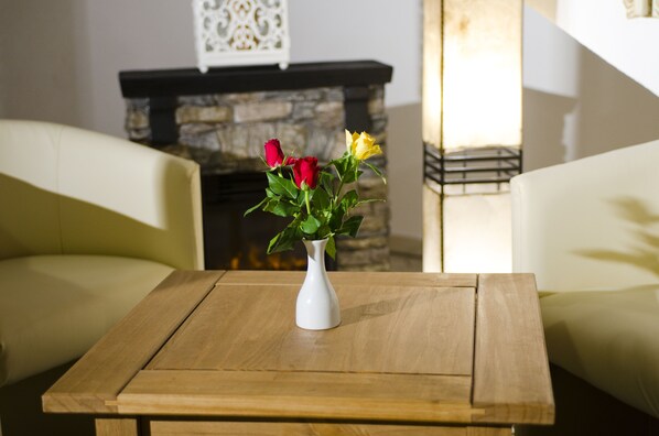 Une table en bois sur laquelle est posé un vase blanc contenant des fleurs rouges et jaunes.