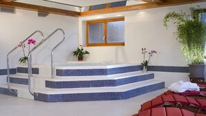 A spa area with a hot tub, steps, and red massage chairs. - Hotel Mutzel (Schluchsee)