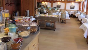 A buffet setup with various food items and beverages, wooden walls, and tables with white tablecloths. - Hotel Mutzel (Schluchsee)