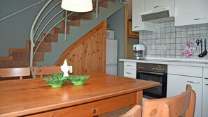 Una cocina con armarios de madera, una encimera blanca y una mesa de comedor de madera con un bol verde.